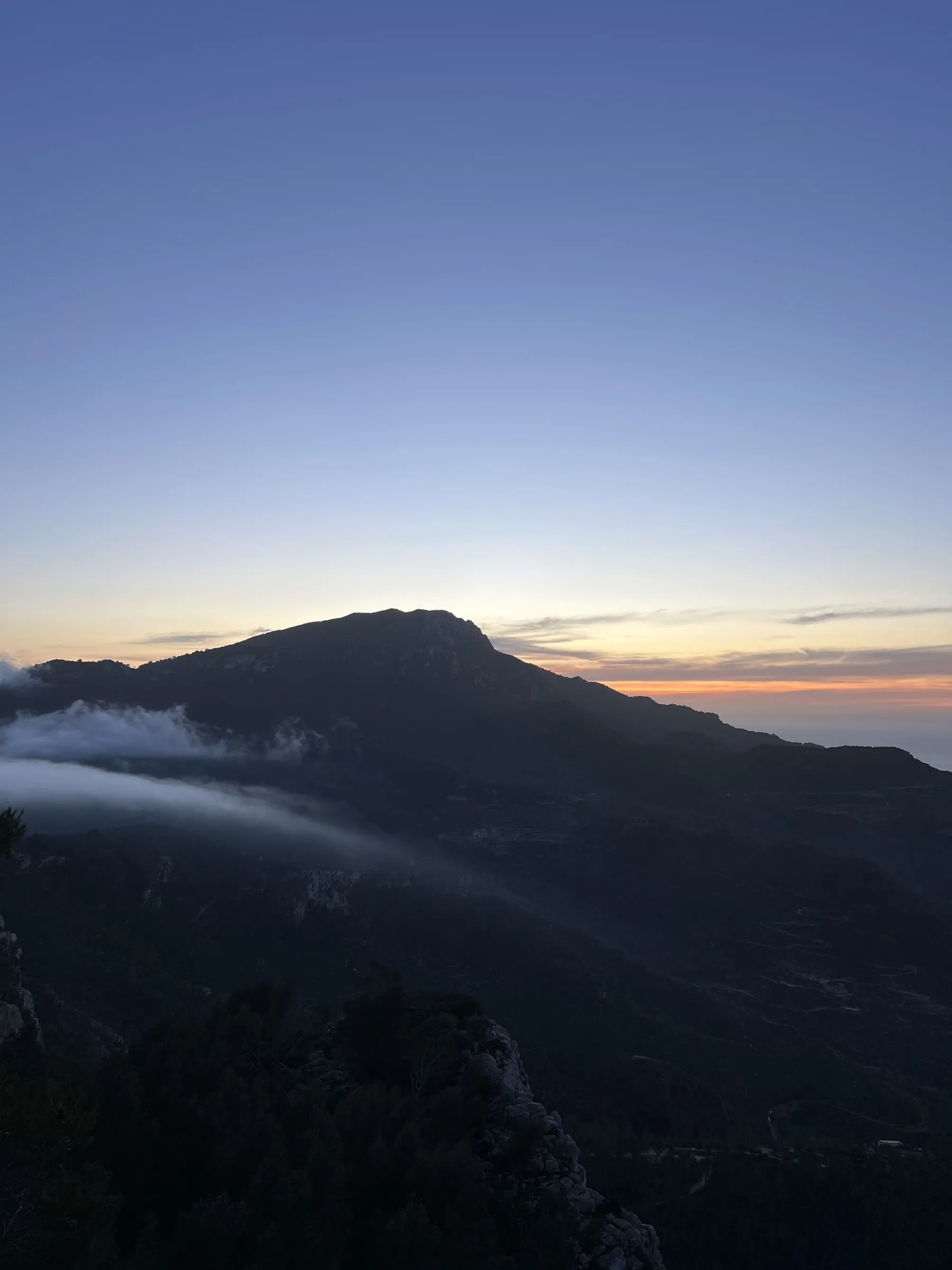 A band of low fog sliding down the mountainside above Banyalbufar as the sun goes down.