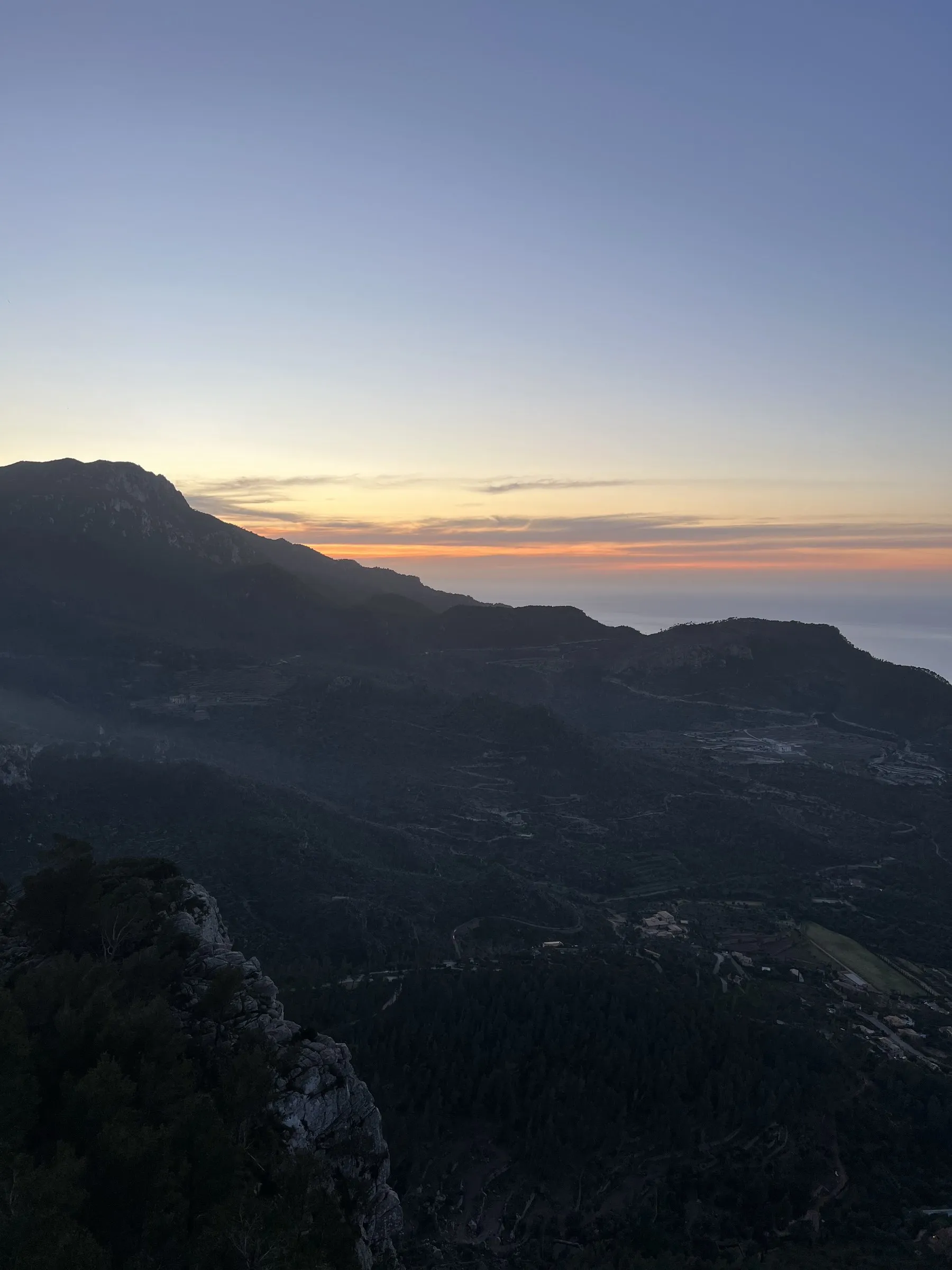 The silhouette of the mountains against the last orange band on the horizon over the sea.