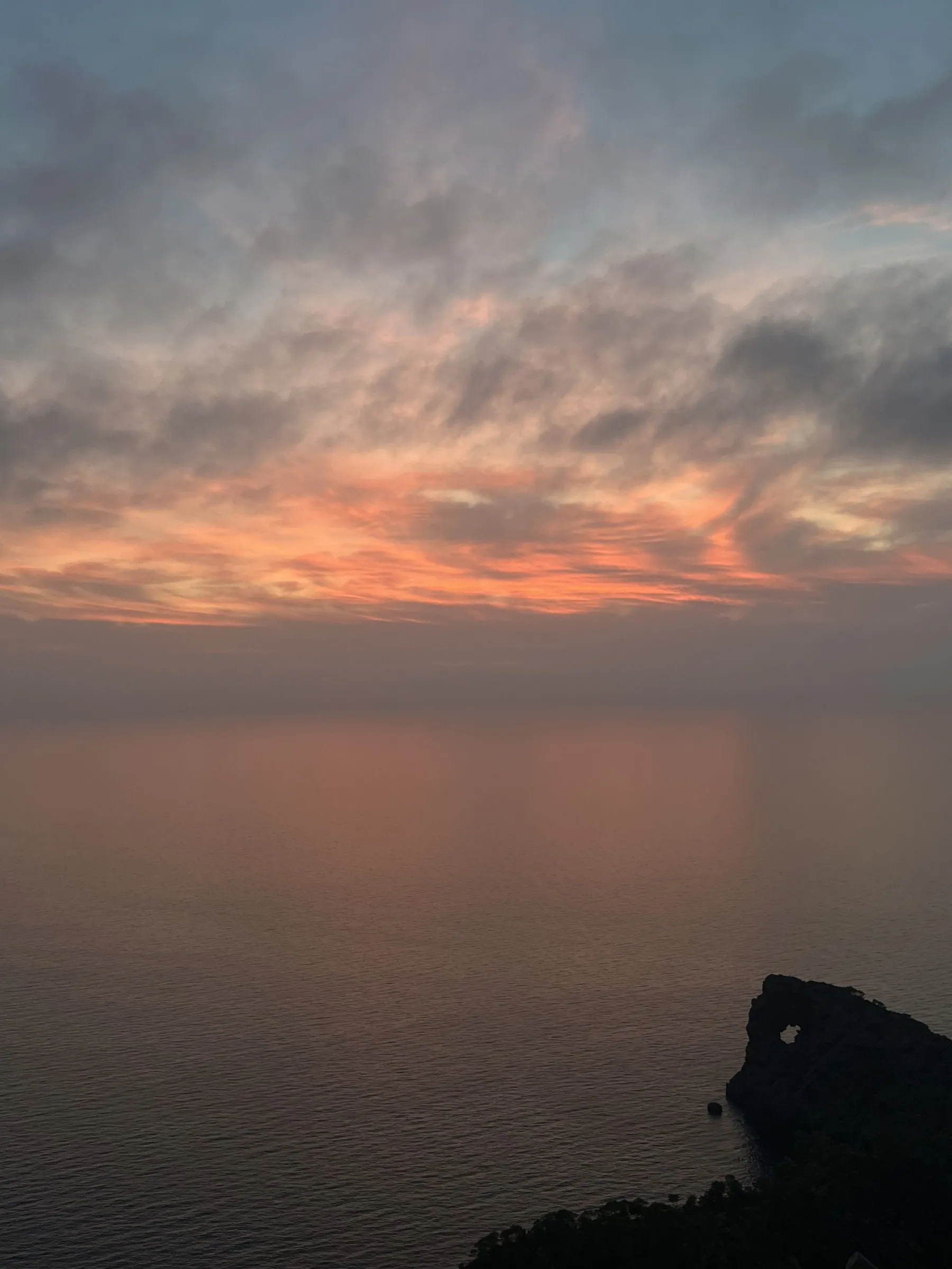 Clouds lit orange over a calm sea at sunset at Cap de ses Salines.