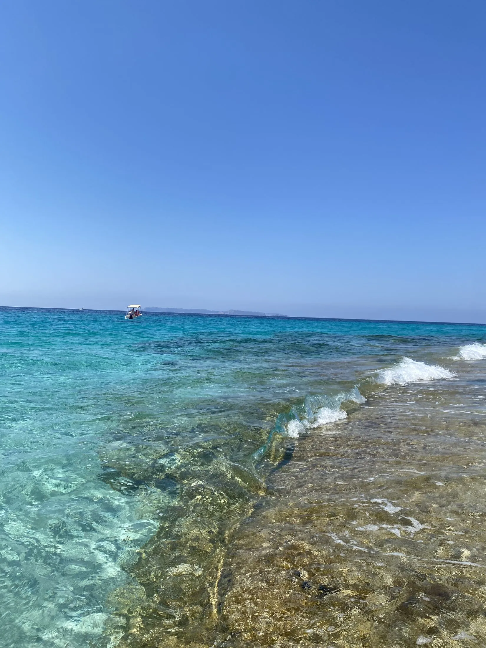 La costa rocosa del Cap de ses Salines con el agua turquesa y transparente rompiendo sobre las piedras.