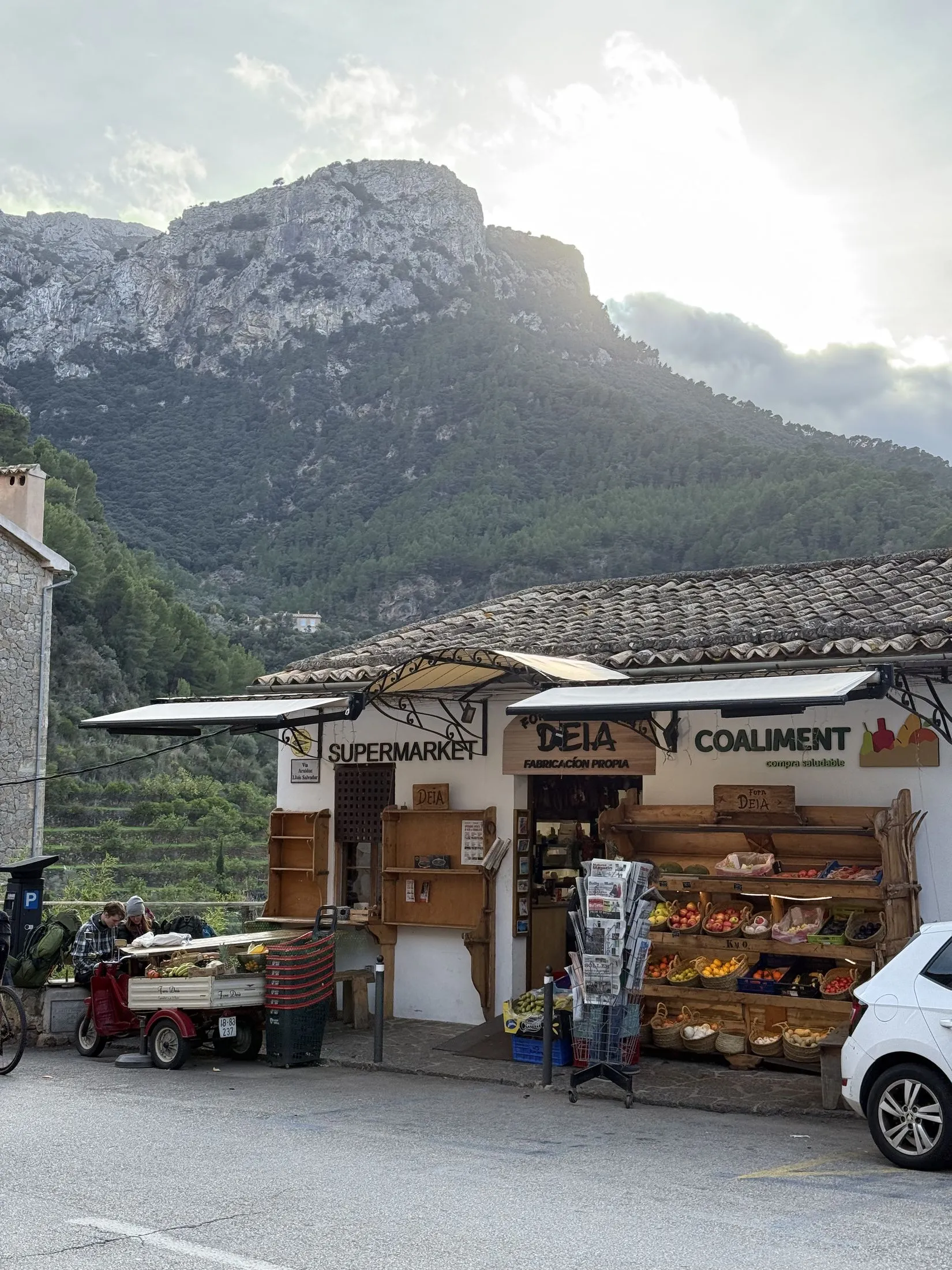 A grocery shop on the main street of Deià, with the bulk of the Teix rising directly behind the village.