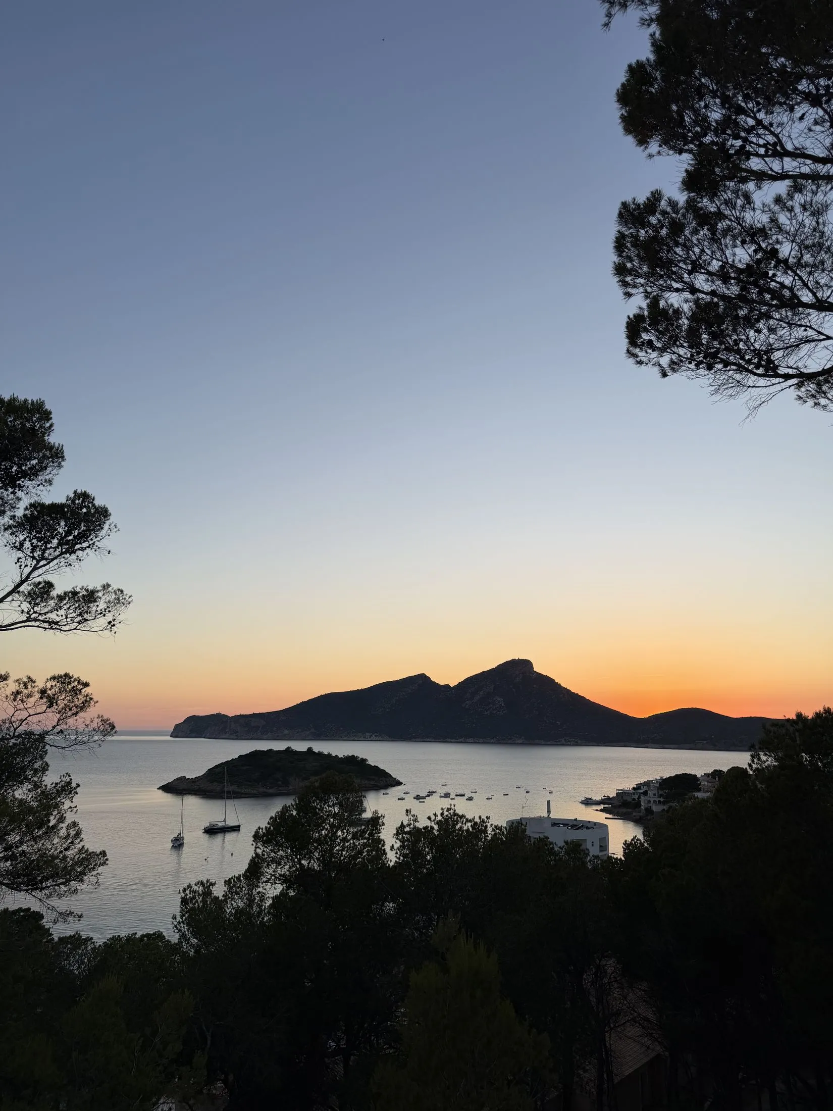 The island of Sa Dragonera silhouetted against an orange sunset sky, seen from Sant Elm.